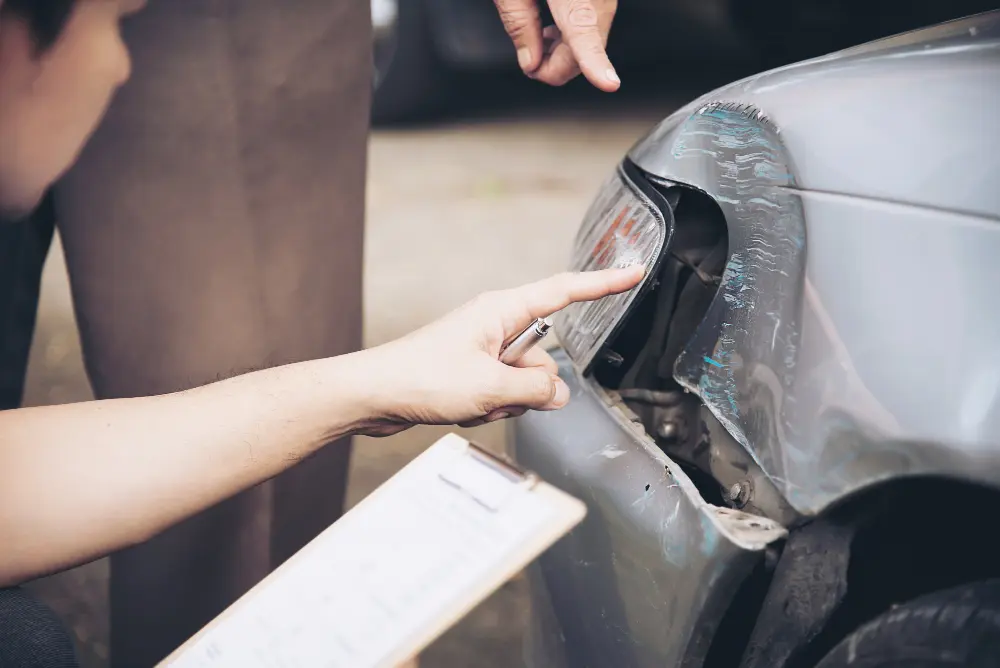 Technician inspecting rear bumper damage on a car after an accident